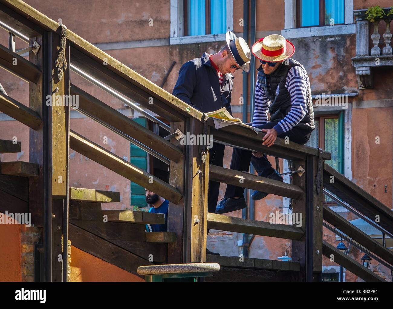 Venediger Gondoliere in Strohhüten lesen eine Zeitung auf einer Holztreppe, Venedig, Venetien, Italien Stockfoto