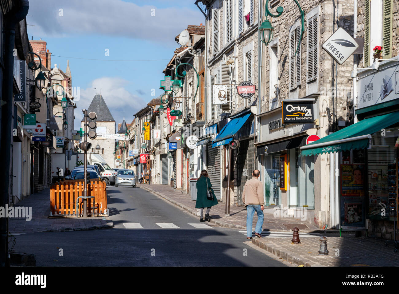 Fußgänger überqueren Sie die Rue Grande (Große Straße) an einem sonnigen Tag. Die Rue Grande mit seinen Bars und Geschäfte ist eine wichtige Straße von Moret-Sur-Loing. Frankreich Stockfoto