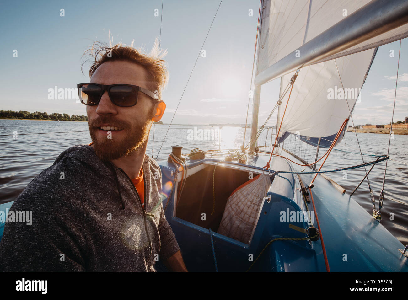 Man steuert Boot mit Deichsel bei Stern während der Fahrt auf dem Fluss im Sommer Tag Stockfoto