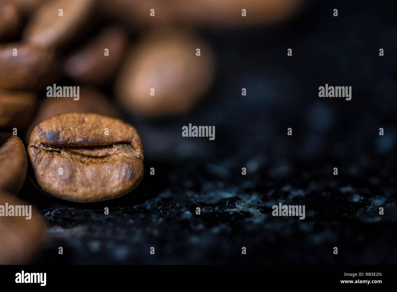 Kaffeebohnen auf schwarzem Marmor Hintergrund, Makroaufnahmen, Platz für ein Logo, Bild oder Text Stockfoto