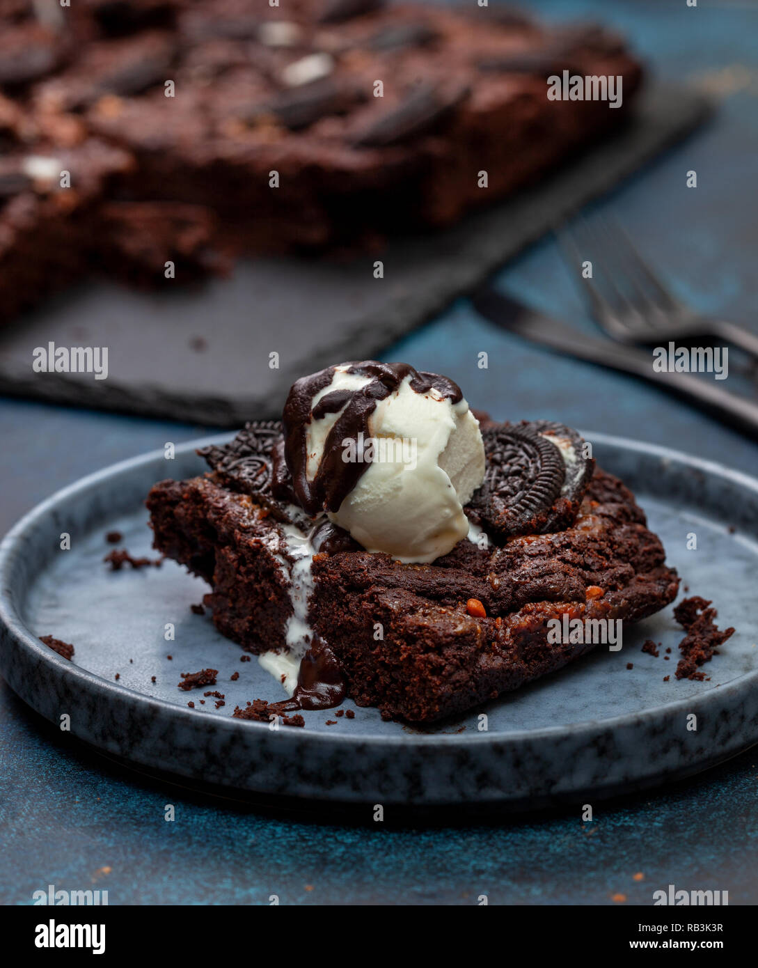Brownie mit oreo und Vanille Eis in einem blauen Platte auf einem blauen Hintergrund close-up Stockfoto