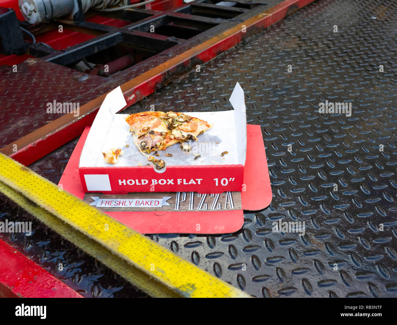 Littering, eine weggeworfene Box mit einer halben Pizza gegessen, auf der Rückseite ein, um die Wiederherstellung des Fahrzeugs Lkw links Stockfoto