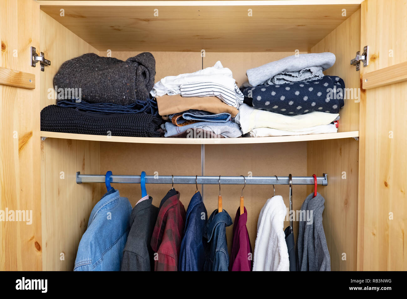 Schlaffe Regal mit viel Kleidung im Schrank. Konzept der Fülle der persönlichen Sachen und Konsumismus. Stockfoto
