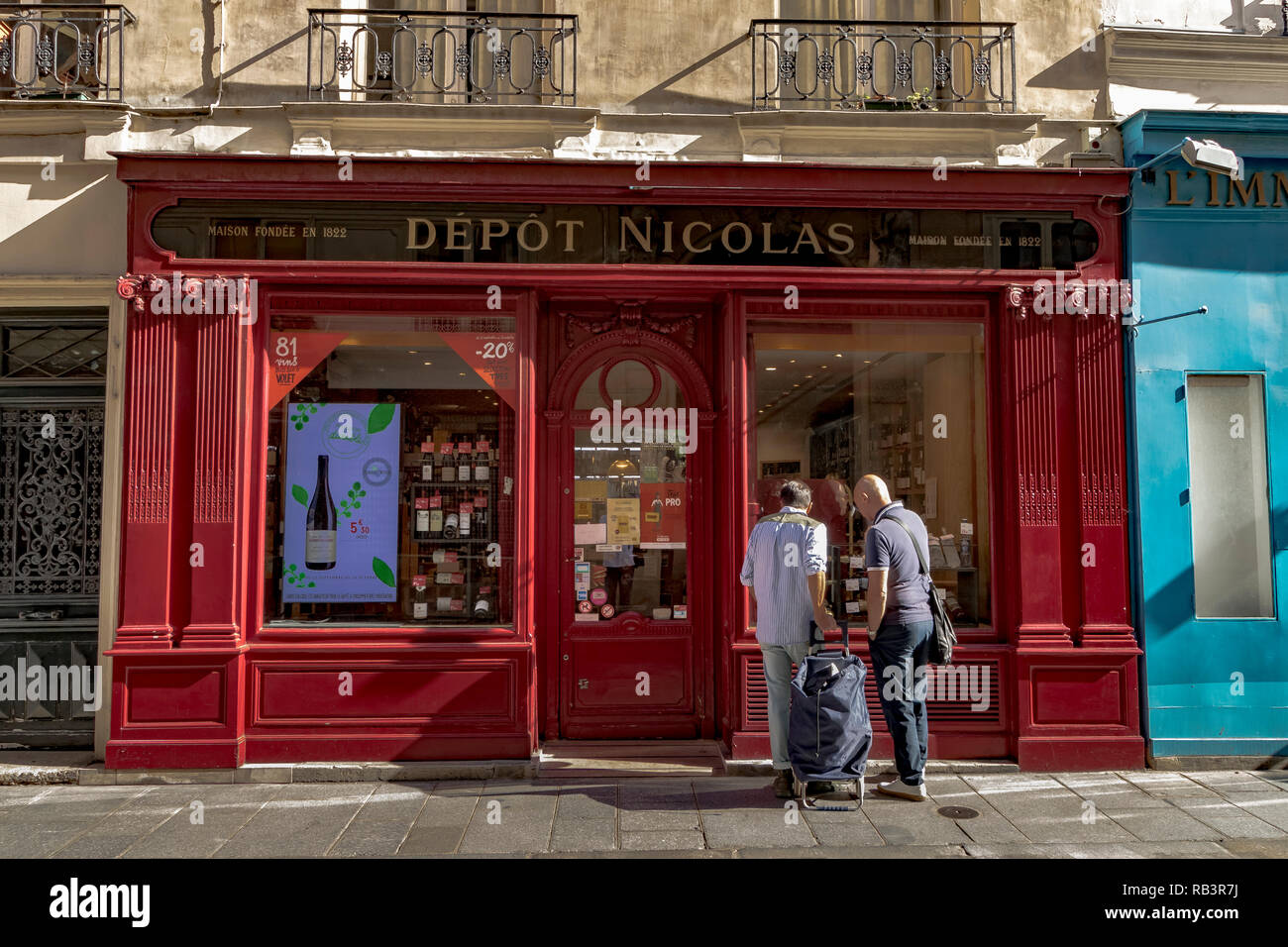 Zwei Leute, die in das Fenster der Depot Nicolas, ein weinhändler Shop auf der rue Saint-Louis en l'Île, Paris, Frankreich Stockfoto