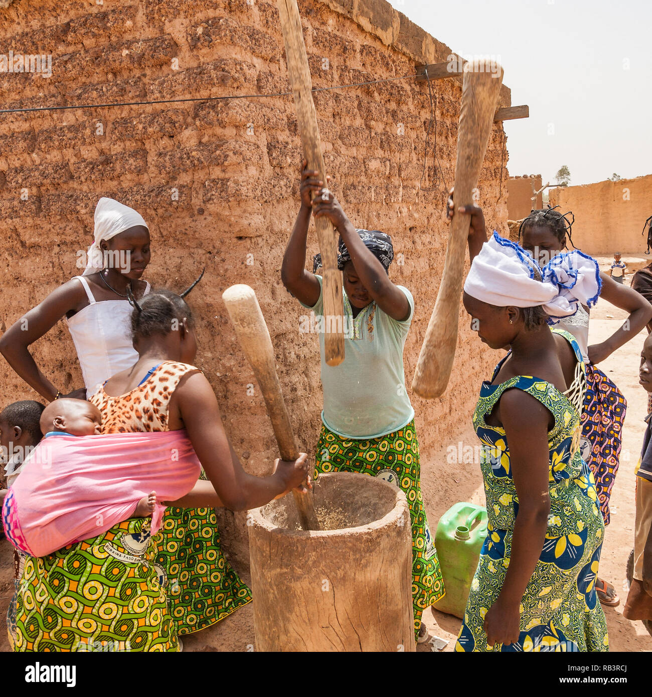 Afrikanische Frauen quetschen Getreide mit traditionellen Holzmöbeln Mörser und Stößel, Ouagadougou, Burkina Faso. Stockfoto