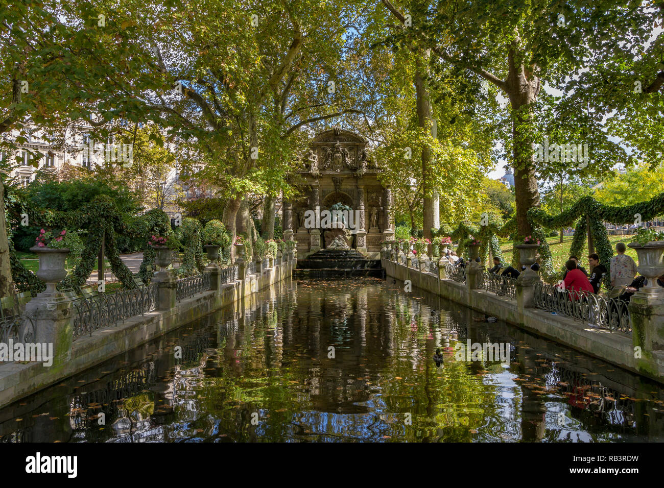 Menschen sitzen am Teich am Medici-Brunnen oder Fontaine de Medicis, einem monumentalen Brunnen, an einem Sommertag im Jardin du Luxembourg, Paris Stockfoto