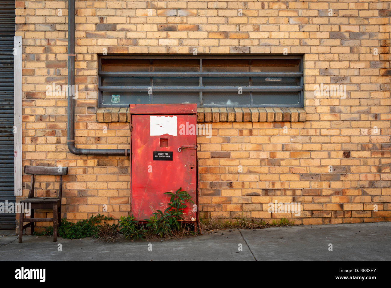 Eine alte rote firebox außerhalb eines alten Mechanik Workshop mit einem hölzernen Stuhl Stockfoto
