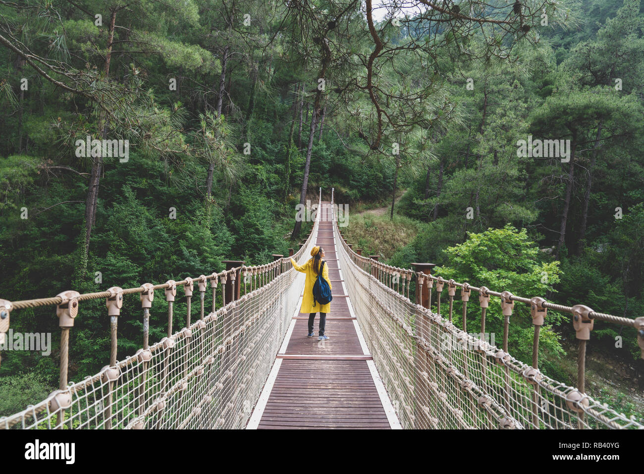 Frau mit regenmantel stehend auf Suspension Bridge. Stockfoto