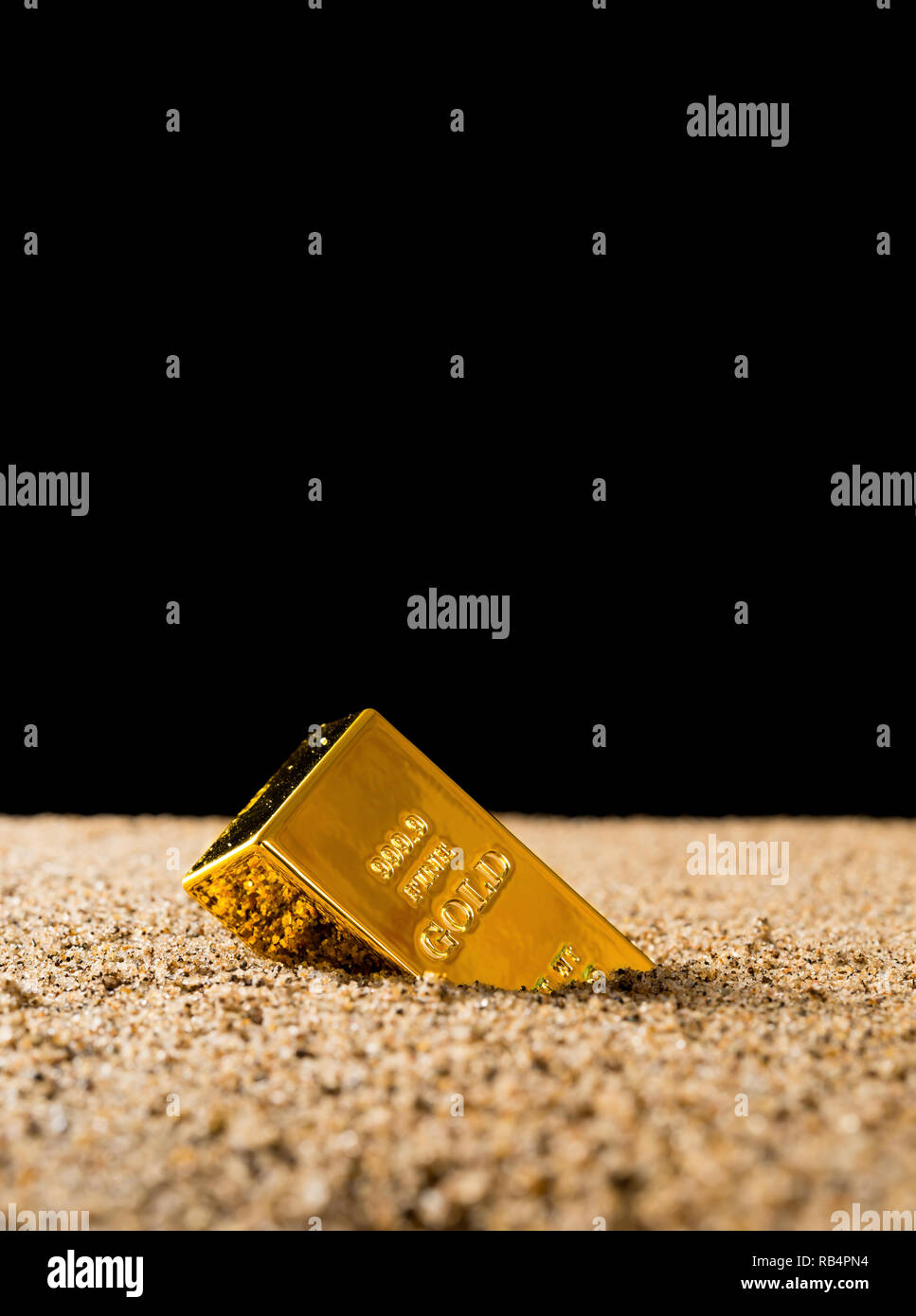 Gold die Hälfte sank in den Sand vor einem schwarzen Hintergrund Konzept der Wert Kollabieren des Gold Stockfoto