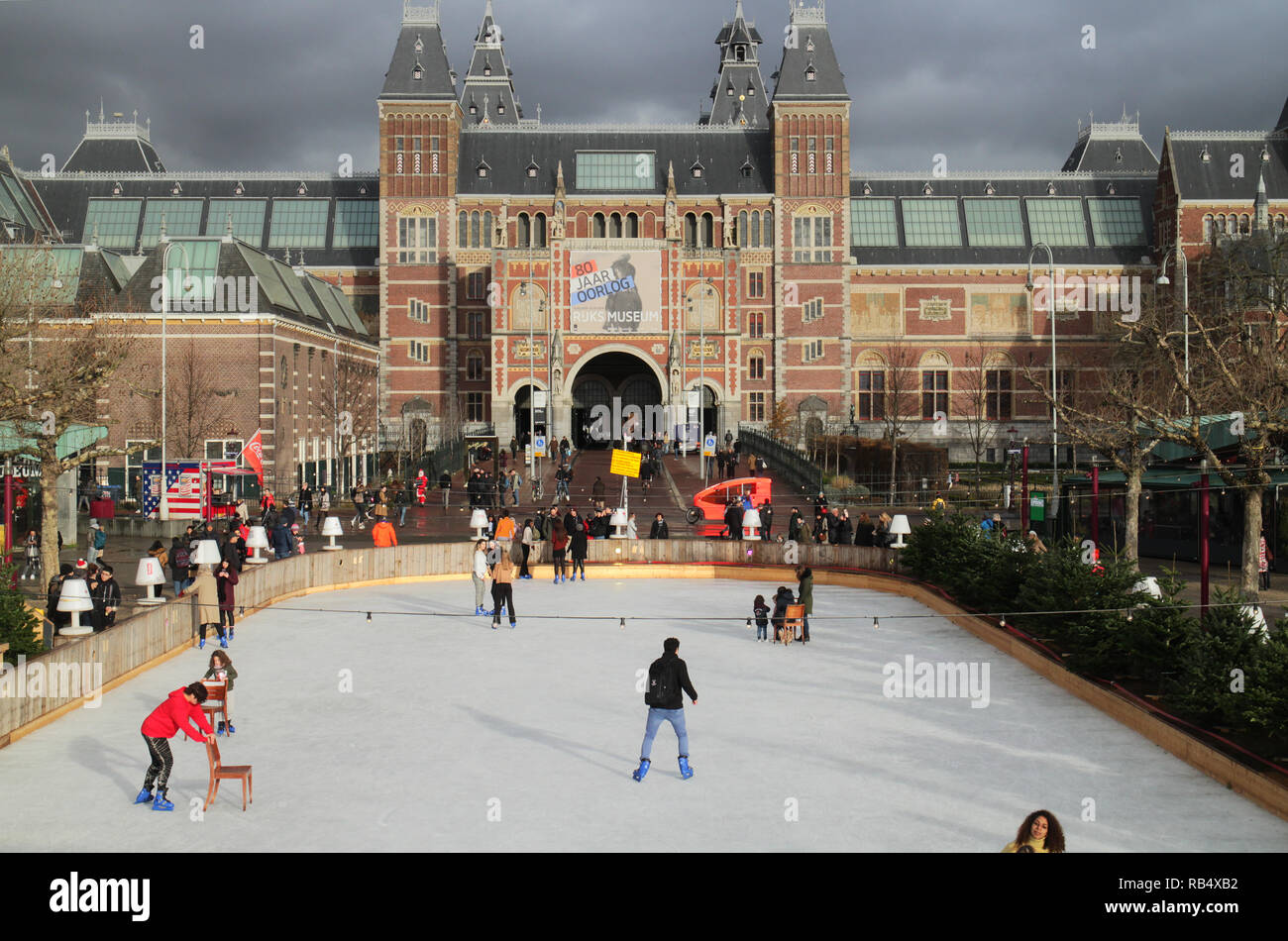 Die Skater auf der Eisbahn im Museum Quadrat, Amsterdam, im Dezember mit dem Rijksmuseum im Hintergrund Stockfoto