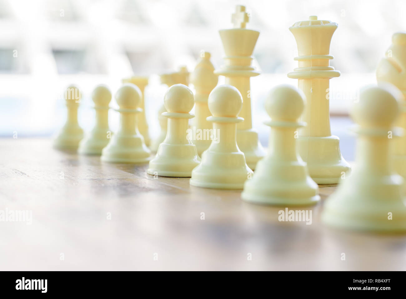 Weiße Stücke mit einem Schachbrett vor einem Spiel. Stockfoto