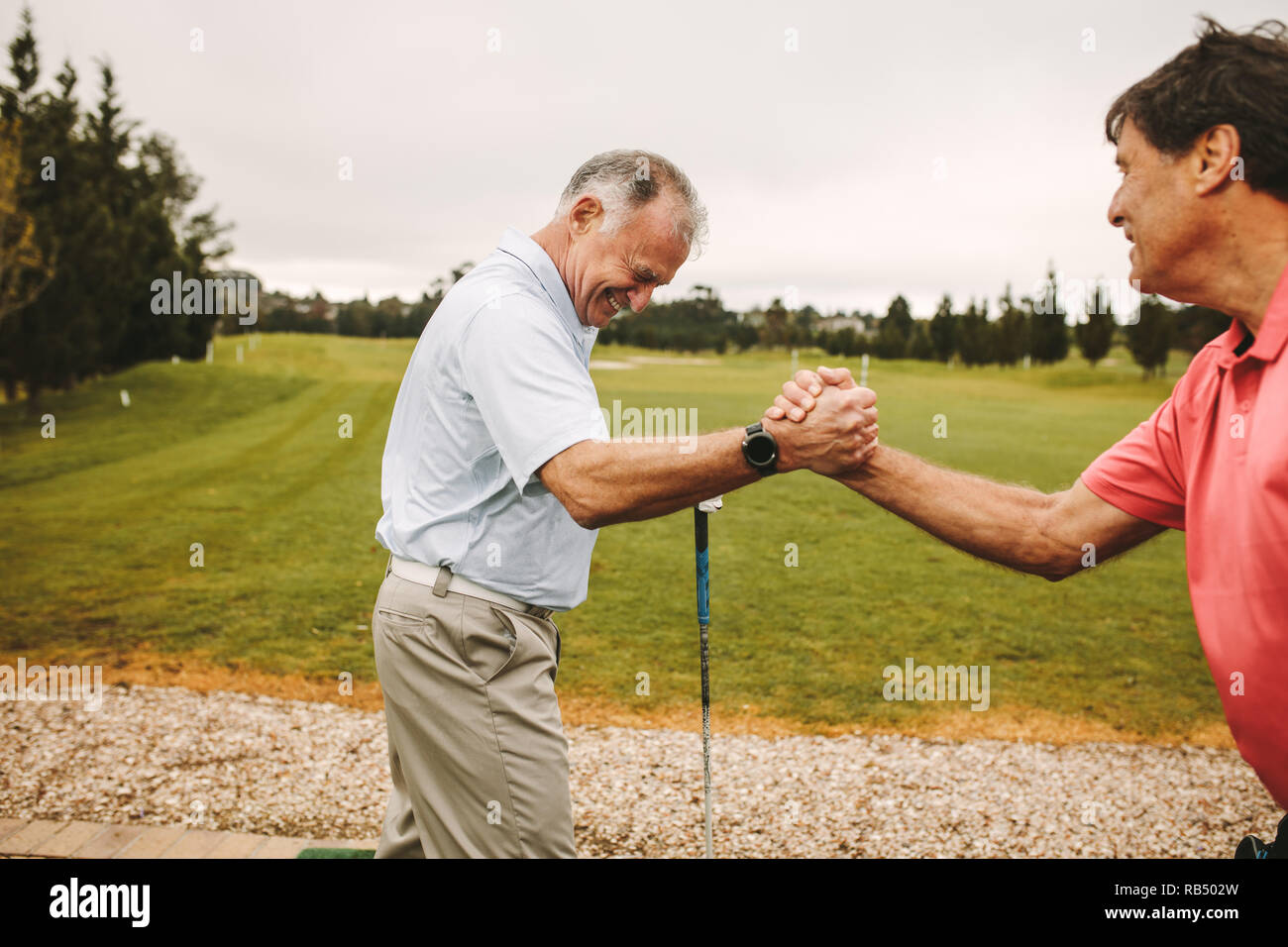 Ältere Golf Spieler Hände schütteln während einer Praxis auf die Strecke fahren. Zwei ältere Golf Spieler Hände schütteln Nach einem Training auf die Strecke fahren. Stockfoto