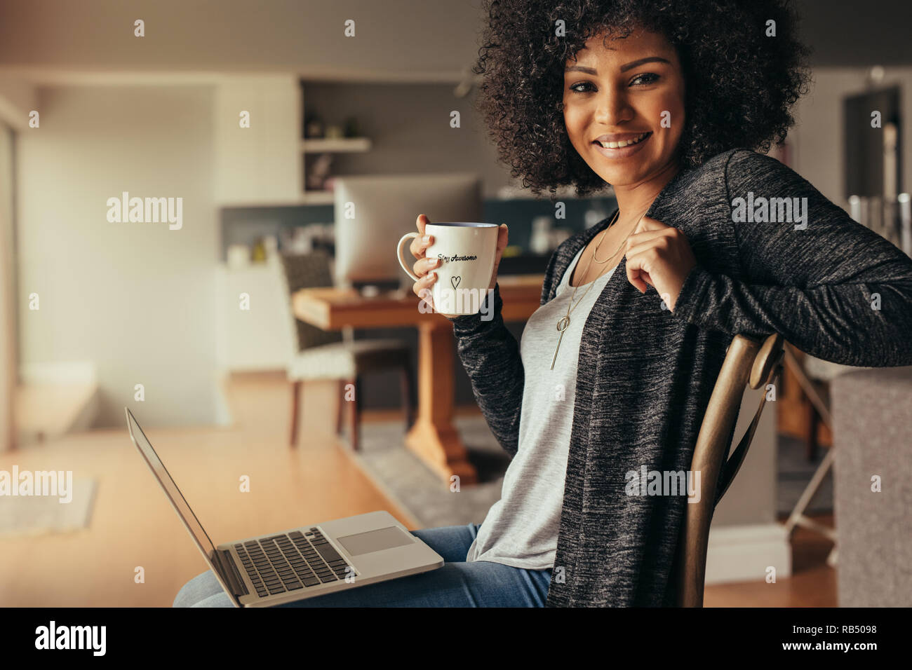 Porträt der schöne junge Frau zu Hause mit Laptop sitzen und Kaffee. Afrikanische Frauen entspannt zu Hause mit Kaffee und Laptop am Cam suchen Stockfoto