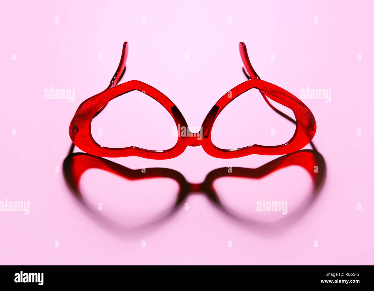 Ein Paar rote herzförmige Sonnenbrille auf rosa Hintergrund. Stockfoto