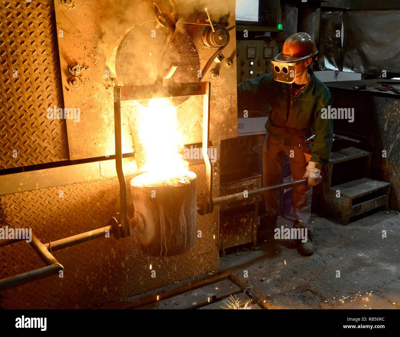 Arbeitnehmer in einer Gießerei gießen ein Werkstück aus Metall - Sicherheit bei der Arbeit und Teamarbeit Stockfoto