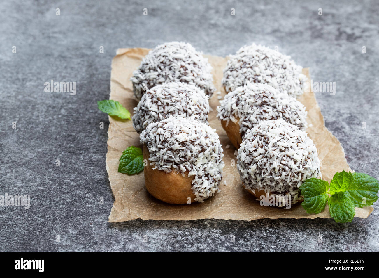 Hausgemachter Windbeutel mit Kokosraspeln auf grau Tisch Stockfoto