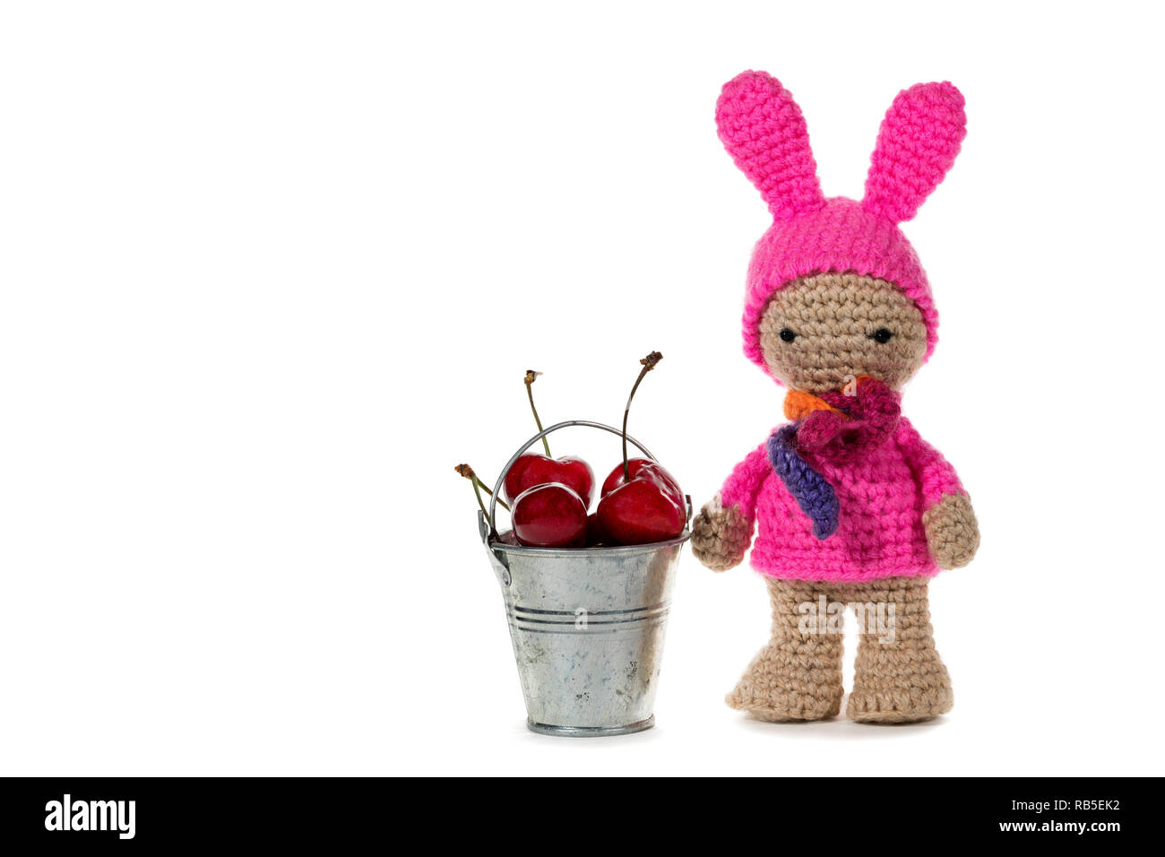 Als bunny crochet Mädchen und ein Metall Eimer mit Kirschen, auf weißem Hintergrund gekleidet. Oder. Handgefertigte Stockfoto