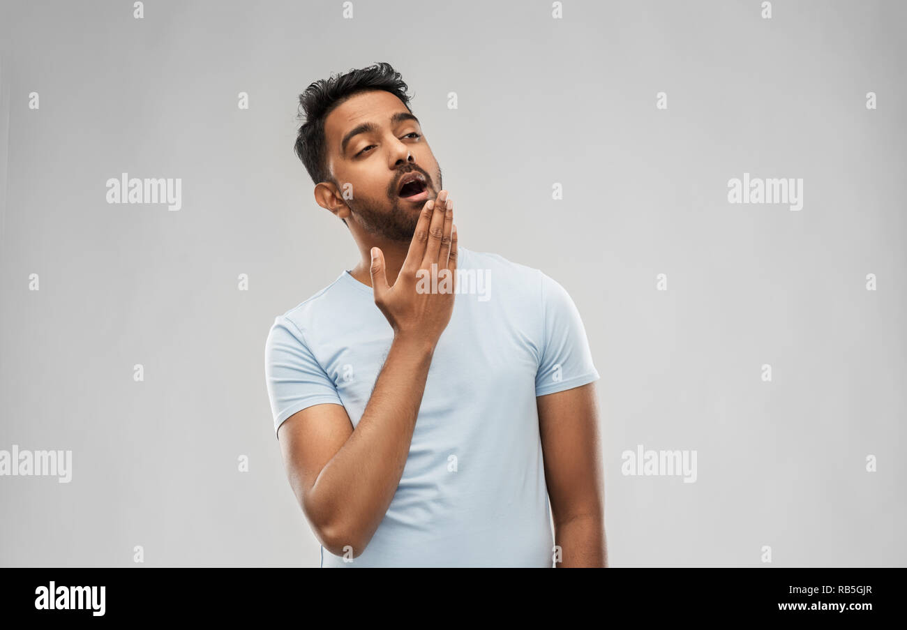 Müde inder Gähnen über grauer Hintergrund Stockfoto