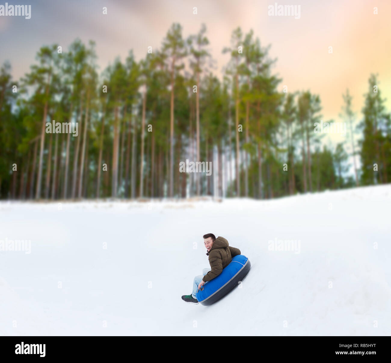 Glückliche junge Mann unten Sliding Hill auf Snow tube Stockfoto