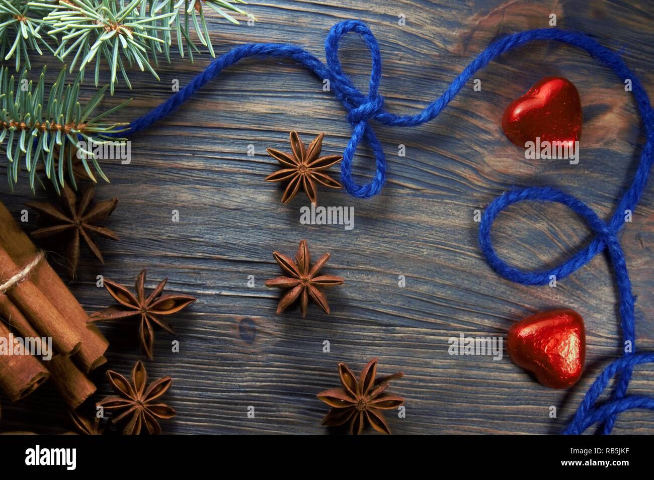 Weihnachten layout Konzept auf Holzuntergrund mit Zimt und Anis Sterne Gewürze, blauem Faden und roten herzförmigen Bonbons Stockfoto