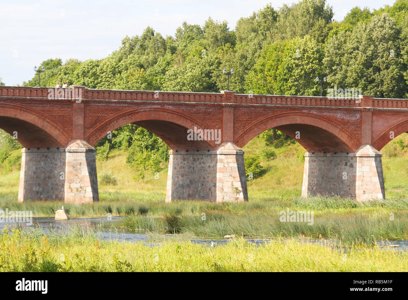 Schön, auf dem Land, Dorf, Blick auf die Altstadt, den alten roten Backstein Brücke über den kleinen Fluss namens Venta. In Lettland - Europa. Stockfoto