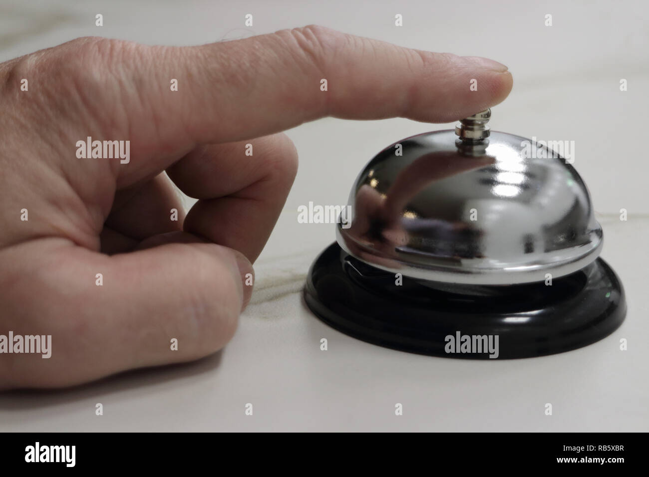 Person Ringe einen Tisch Glocke an der Rezeption des Hotels Stockfoto