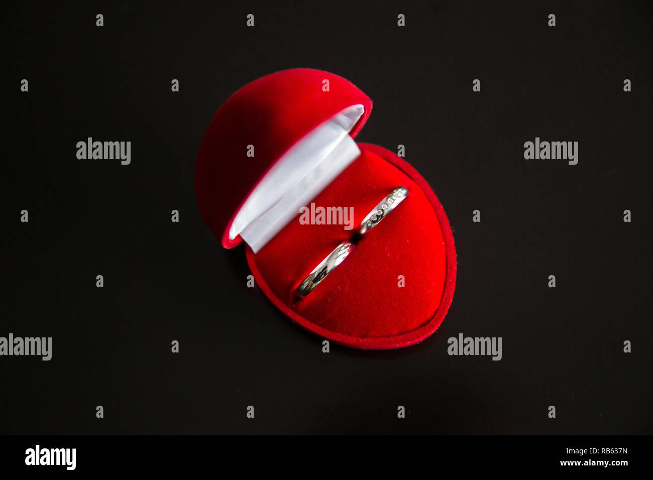 Trauringe in einem roten herzförmigen Samt Schmuckschatulle Stockfoto