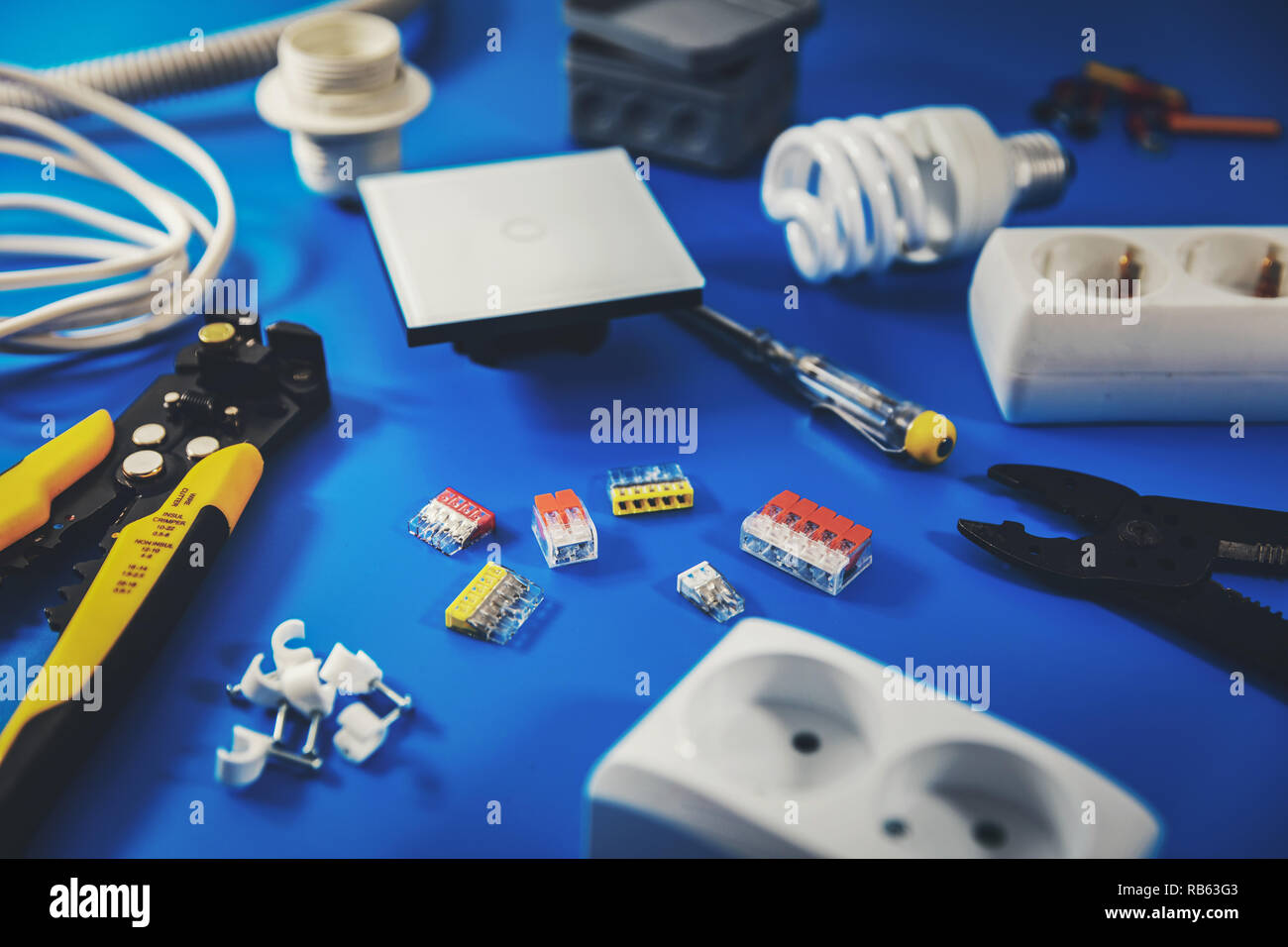 Elektrische Installation - Elektriker Werkzeuge und Ausrüstung auf blauem Hintergrund Stockfoto