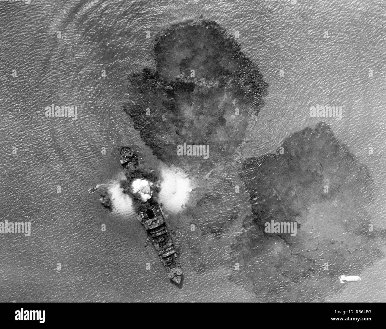 Foto einer 7.000 t japanisches Handelsschiff nach einem direkten Treffer durch indische Luft Task Forces in der Nähe von Rangun, Indien. Kleine Yachten mit Crew Mitglieder besetzt gesehen werden kann. Die Gewässer sind mit Öl bedeckt. Vom 1943 Stockfoto
