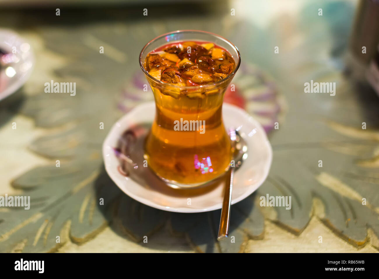 Ein klares Glas Tasse traditionellen Türkischen apfeltee mit Bits von Apple in den Drink auf einem weißen Untertasse mit Teelöffel, Istanbul, Türkei Stockfoto