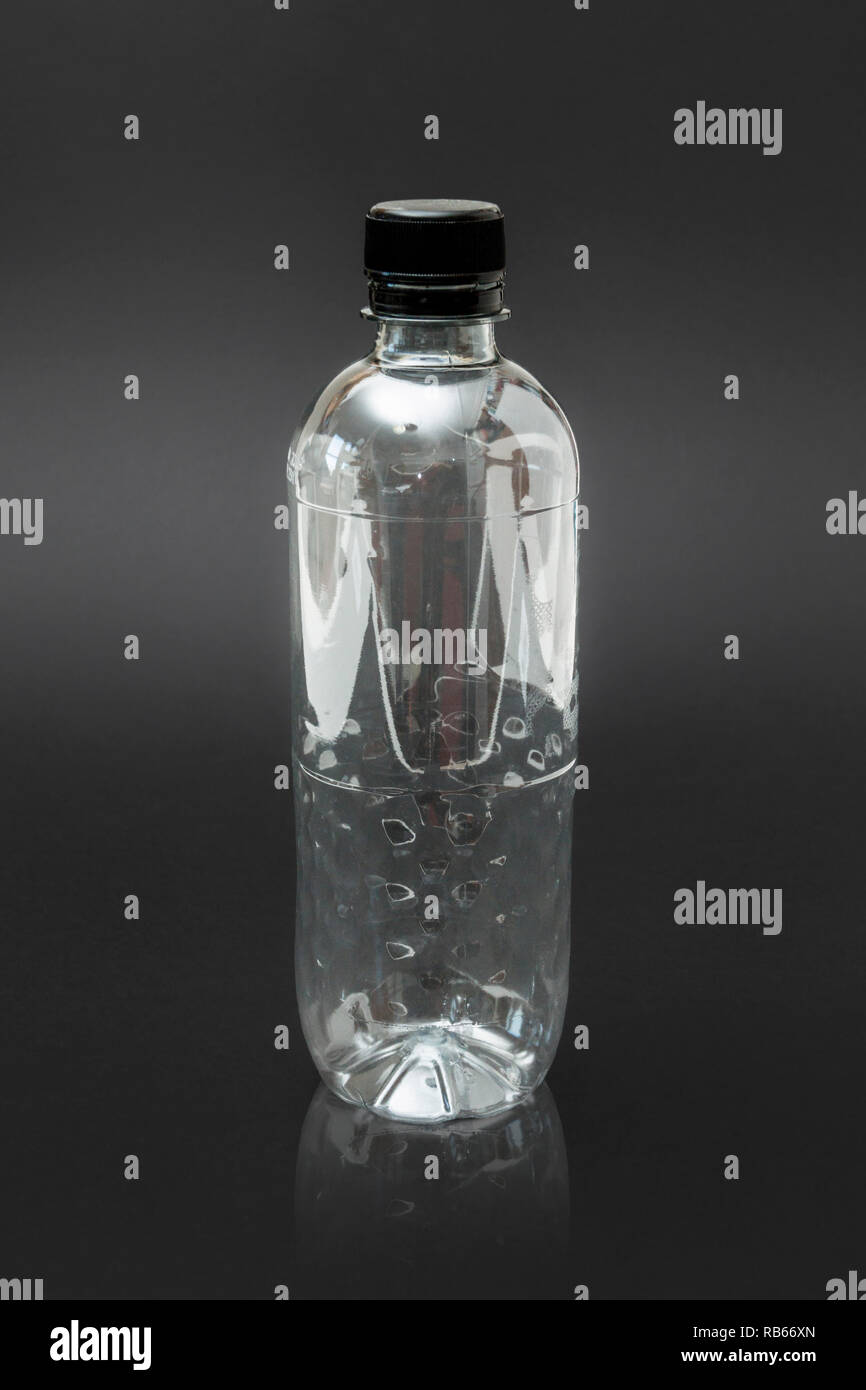Eine leere Generic single use Plastikwasserflasche auf schwarzem Hintergrund, ohne Etikett Stockfoto
