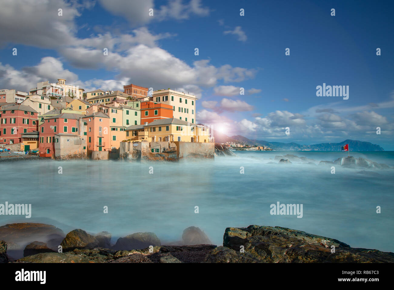 Bunte waterfront Gebäude in Boccadasse, Italienische Riviera, Italien in einem niedrigen Winkel Blick über Felsen und Meer an einem bewölkten Himmel Tag Stockfoto