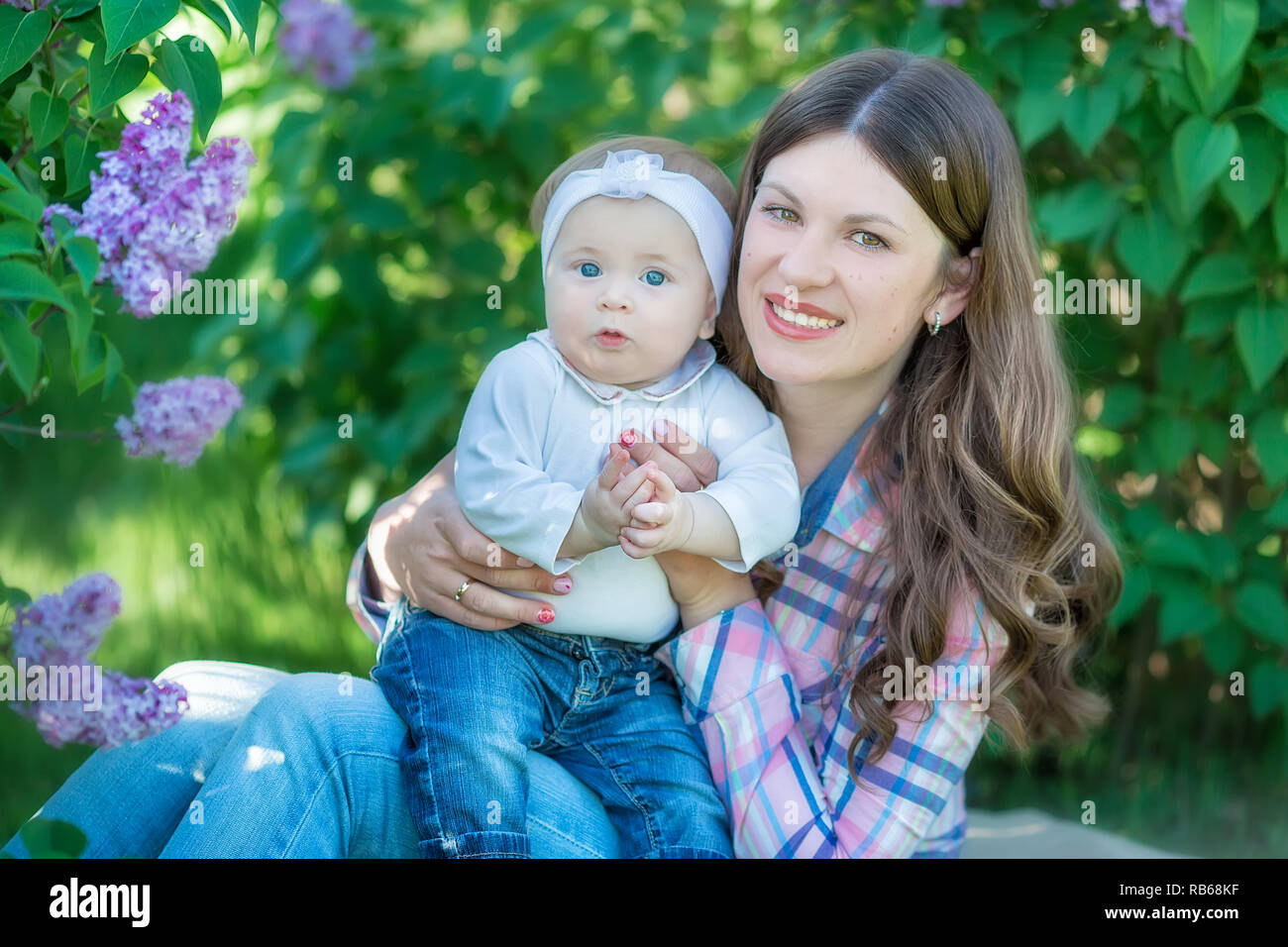 Glückliche Mutter und Tochter mit grüne Äpfel im Garten der blühende Flieder. Stockfoto