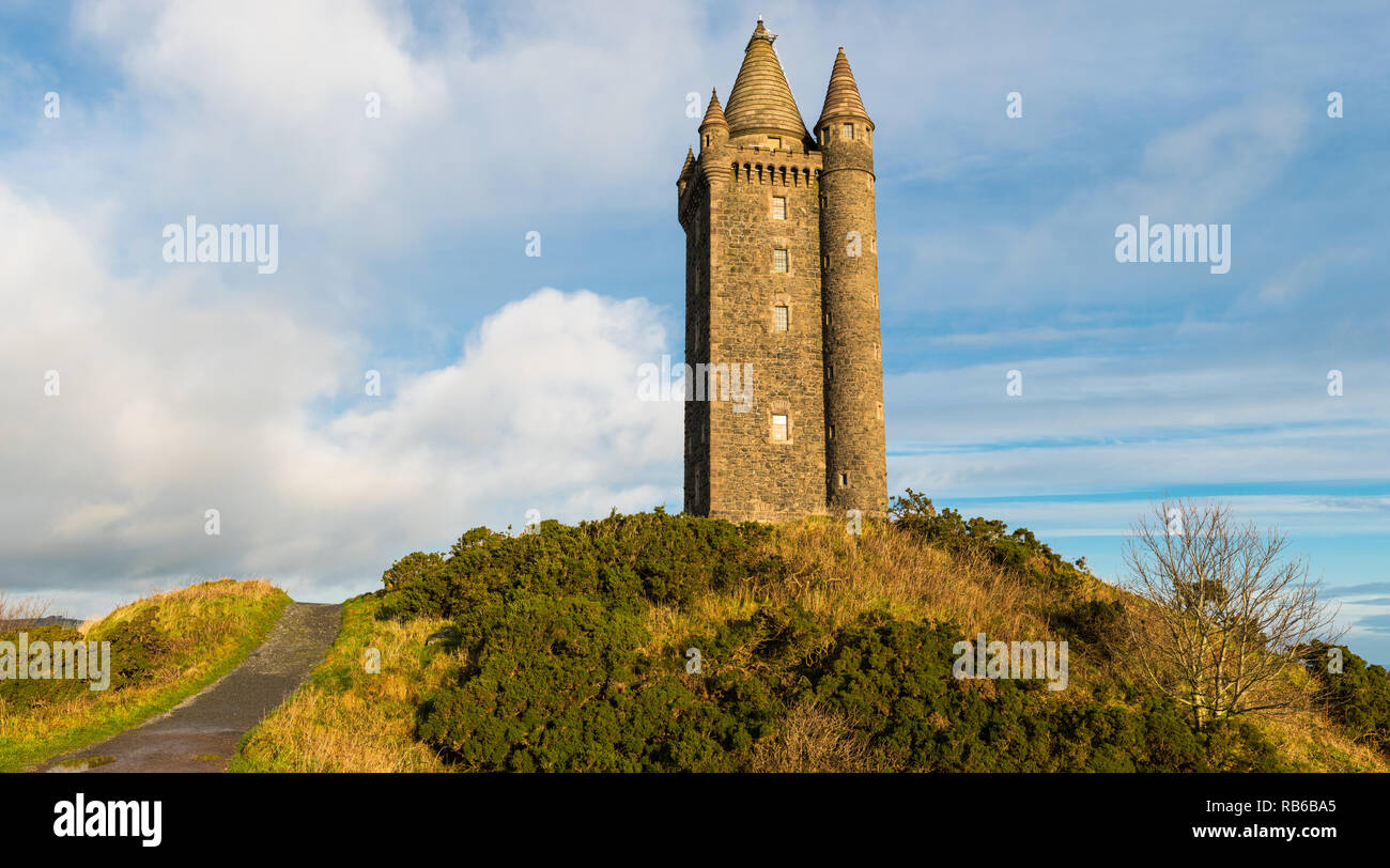 Panoramablick auf einen Weg zu einer alten Burg auf einem Hügel unter einem blauen Himmel mit weißen Wolken Puffy Stockfoto