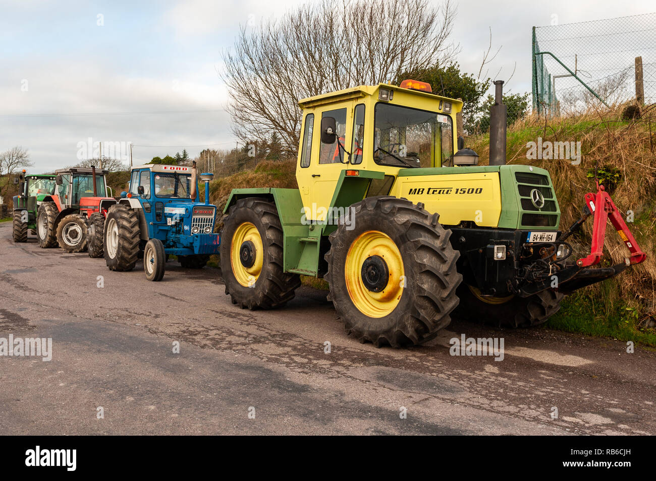 Traktoren auf der Seite einer Straße geparkt, bevor eine liebe Traktor laufen in Glandore, West Cork, Irland. Stockfoto