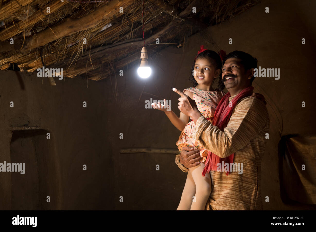Ländlichen indischen Vater mit Tochter freut sich über das Leuchten der Lampe und Strom ihre Heimat erreicht Nach langen warten Stockfoto