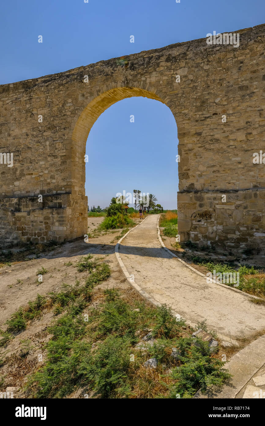 Zentrale arch in der aquädukt in Larnaca, Zypern. Schuß hat ein blauer Himmel und zeigt einen Weg, durch den Arch und darüber hinaus in Richtung Palm tr Stockfoto