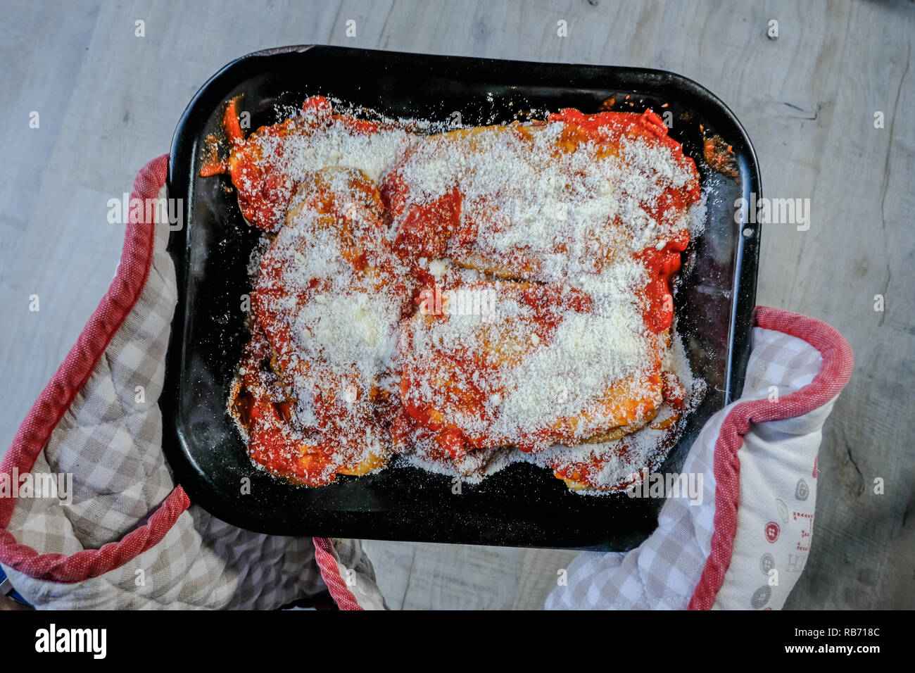 Ungekochte Speise der Aubergine parmigiana in einem Ofen Handschuh statt und bereit, in den Ofen zu kochen zu rutschen. Stockfoto