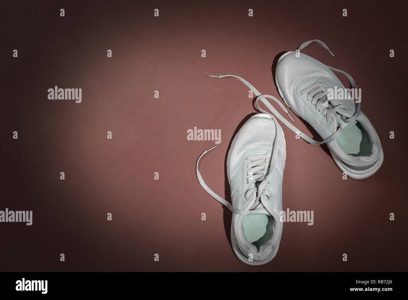 Trendige casual Laufschuhe auf braunem Hintergrund. Ansicht von oben, minimalistisch, flach. Kopieren Sie Platz. Stockfoto