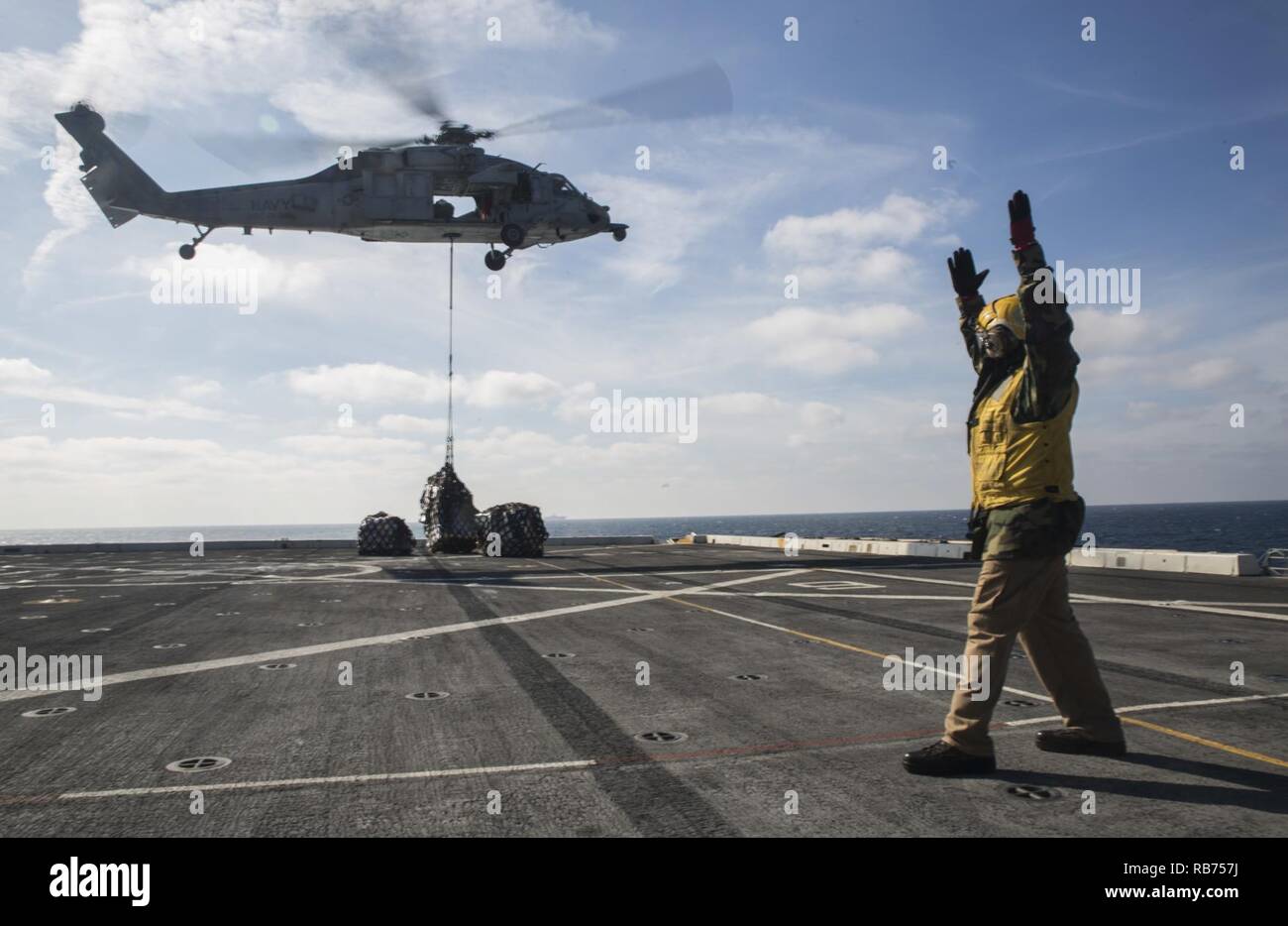 Chief Petty Officer Eugene Williams, eine Landung einweisende mit der Luft Abteilung an Bord der USS Mesa Verde LPD (19), leitet ein MH-60S Seahawk während einer vertikalen Nachschub für den Amphibischen bereit Gruppe Marine Expeditionary Unit Übung Dez. 8, 2016. Während der dreiwöchigen Ausbildung evolution, Marines wird eine breite Palette von Maßnahmen und Szenarien die Verbesserung der Interoperabilität und amphibische Kriegsführung Fähigkeiten mit ihren Marine Pendants bekämpfen. Auffüllung auf See ist entscheidend für die bataan Amphibious Ready Gruppe selbst unterstützen, während im Gange. Stockfoto