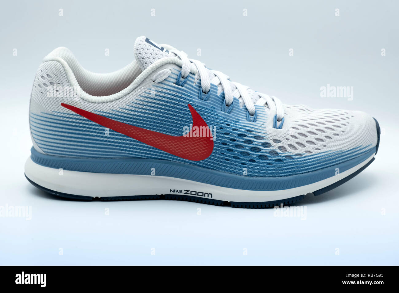 Seitliche Sicht auf eine blau-weiße Nike Pegasus 34 Trainer mit einem roten Swoosh Logo Ausschneiden auf weißem Hintergrund Stockfoto