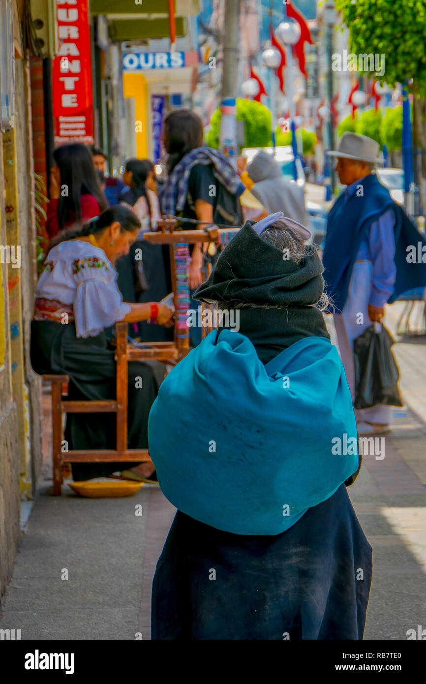 OTAVALO, Ecuador, November 06, 2018: Nicht identifizierte Frau mit einem türkis Tasche und beobachten die handgemachten Armband auf dem Bürgersteig in der Stadt Otavalo. Stockfoto