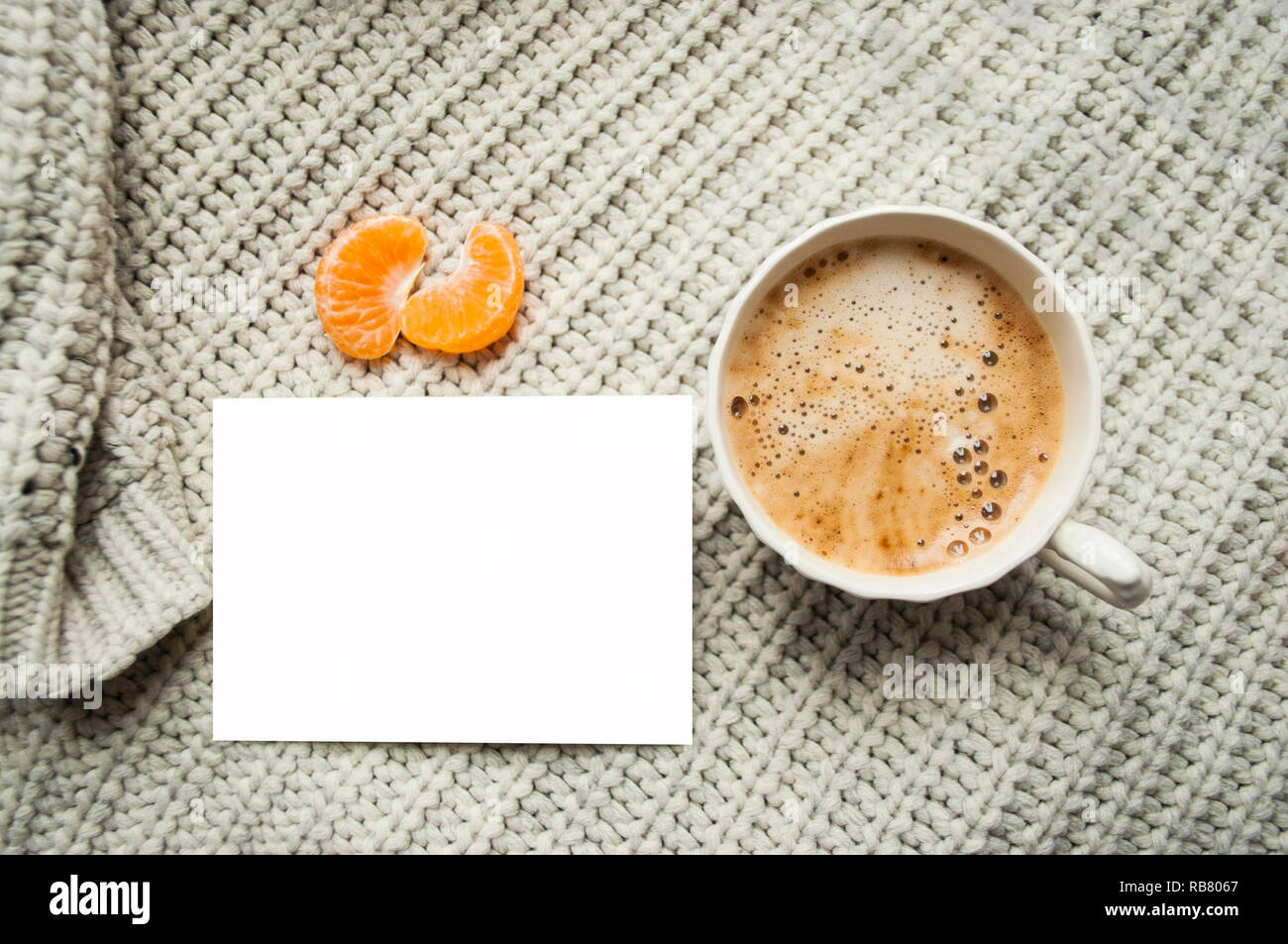 Winter gemütliche Konzept. Grauer Strickpullover, Tasse Tee, geschenkset und Uhren auf grauem Hintergrund. Stockfoto