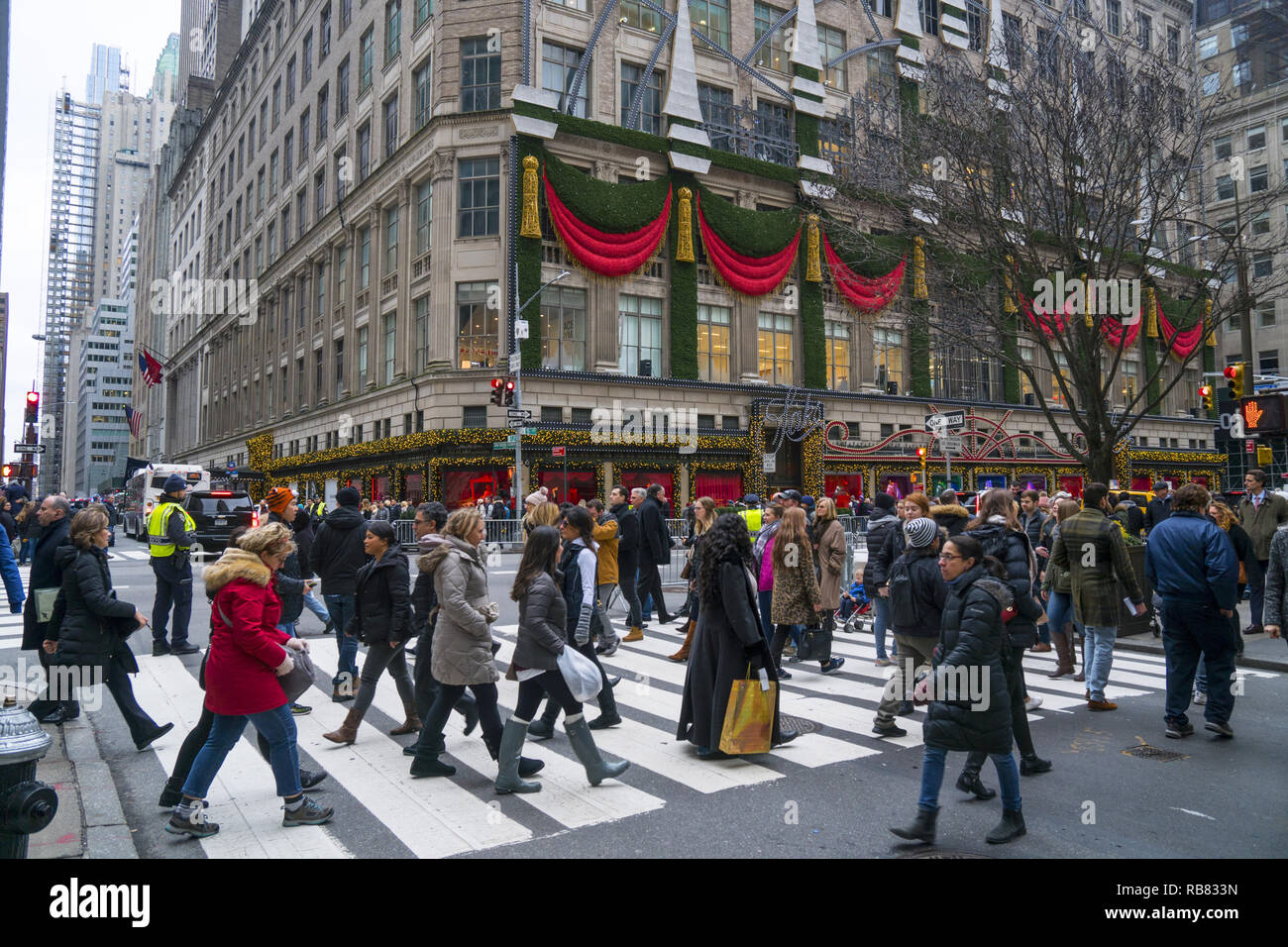 Menschenmassen entlang der 5th Avenue und 50th St. am Rockefeller Center mit Saks 5th Avenue Kaufhaus für die Weihnachtszeit an der Ecke eingerichtet. New York City Stockfoto