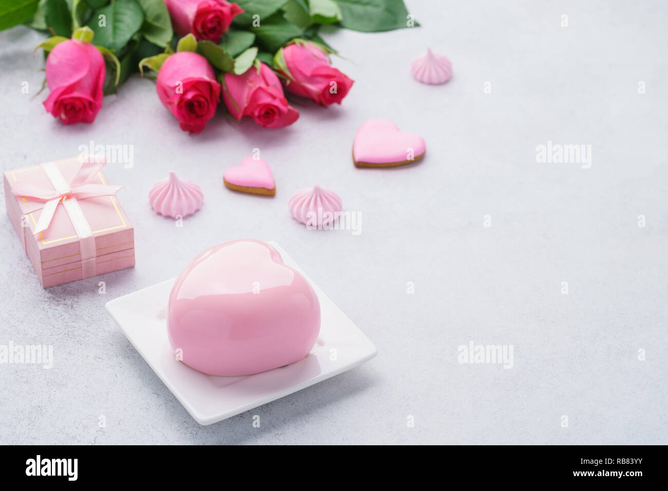 Romantisches Frühstück Konzept mit herzförmigen Mousse Cake, Geschenkbox und Blumen im Hintergrund für Valentines Tag. Kopieren Sie Platz. Stockfoto