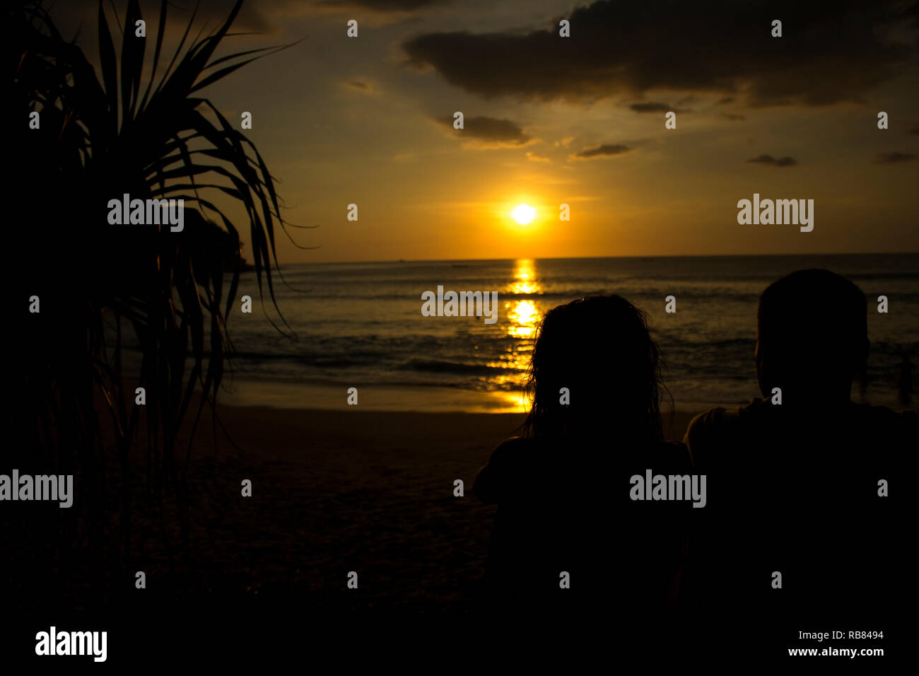 Paar beobachten schönen Sonnenuntergang am Strand Stockfoto