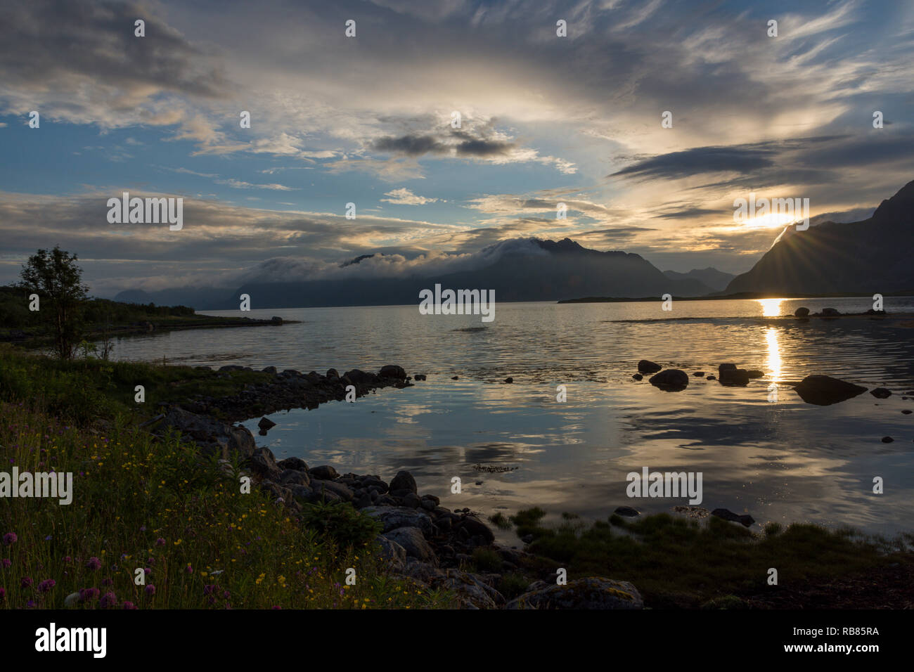 Romantischer Sonnenuntergang der Mitternachtssonne hinter den Bergen und Meer auf den Lofoten in Norwegen, Europa. Genommen nördlich von henningsvær, Vågan, Nordland Stockfoto