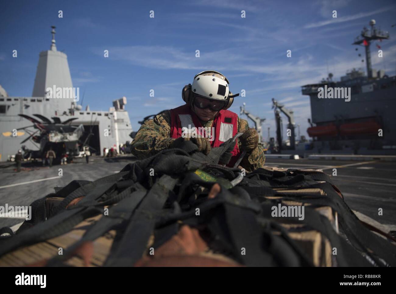 Ein Marine mit dem 24 Marine Expeditionary Unit Hubschrauber support team unfastens den Transport Bänder aus Lieferungen an Bord der USS Mesa Verde (LPD 19) während einer vertikalen Nachschub für den Amphibischen bereit Gruppe Marine Expeditionary Unit Übung Dez. 8, 2016. Während der dreiwöchigen Ausbildung evolution, Marines wird eine breite Palette von Maßnahmen und Szenarien die Verbesserung der Interoperabilität und amphibische Kriegsführung Fähigkeiten mit ihren Marine Pendants bekämpfen. Auffüllung auf See ist entscheidend für die bataan Amphibious Ready Gruppe selbst unterstützen, während im Gange. Stockfoto