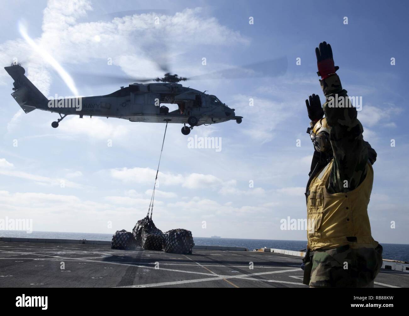 Chief Petty Officer Eugene Williams, eine Landung einweisende mit der USS Mesa Verde LPD (19), führt eine MH-60S Seahawk Helikopter liefern cargo Paletten auf dem Flugdeck der USS Big Horn (T-AO 198) Mutterschiff auf Dez. 8, 2016 während einer vertikalen Nachschub während der Amphibischen bereit Gruppe Marine Expeditionary Unit Übung Dez. 8, 2016, als die USS Bataan über den Horizont. Während der dreiwöchigen Ausbildung evolution, Marines wird eine breite Palette von Maßnahmen und Szenarien die Verbesserung der Interoperabilität und amphibische Kriegsführung Fähigkeiten mit ihren Marine Pendants bekämpfen. Verstärkung bei s Stockfoto