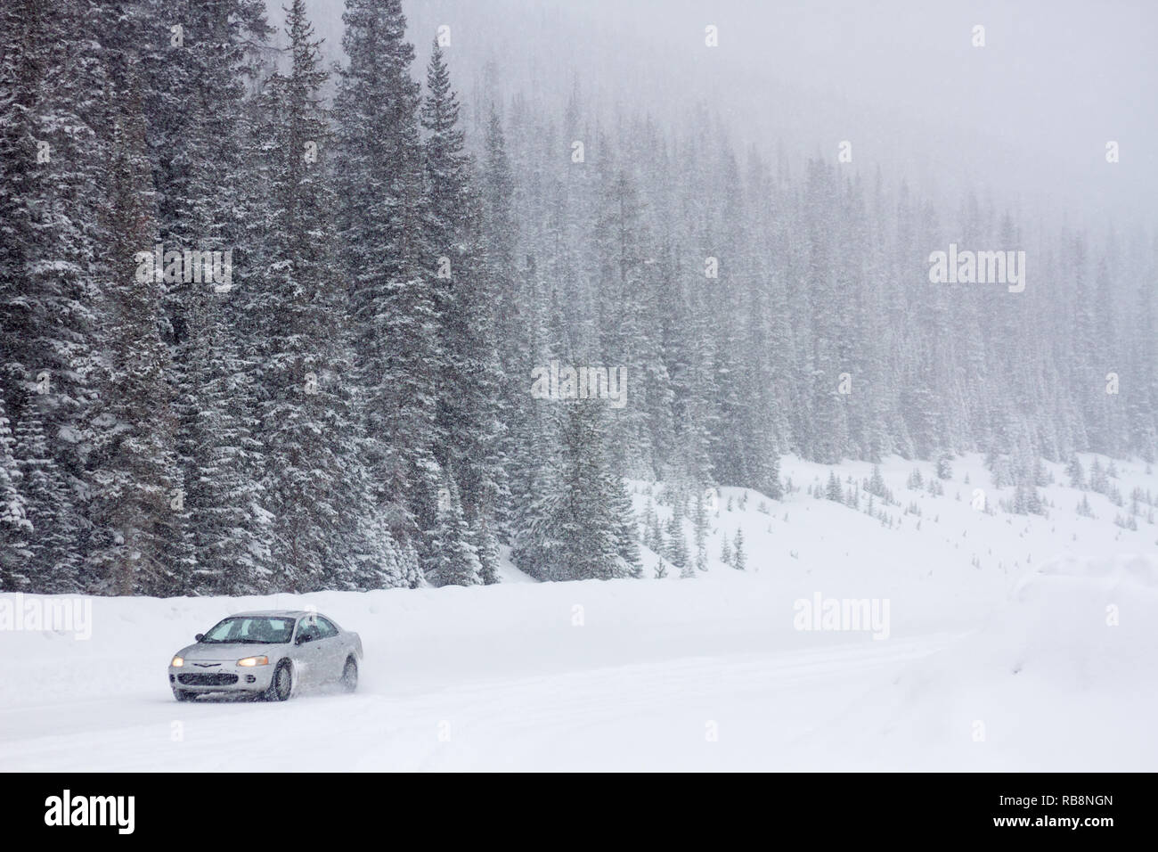 Auto reisen Schotter, Schnee, Berg Straße in Kananaskis, Alberta, Kanada. Winterreifen im Winter Wetter wünschenswert, insbesondere in abgelegenen Gebieten. Stockfoto